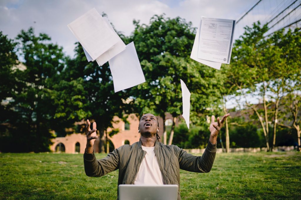Learner throwing paper in the air and working on a laptop while offering CV advice