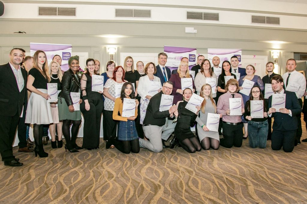 Protocol learner case studies, shown by having dozens of learners holding their achievement certificates on stage